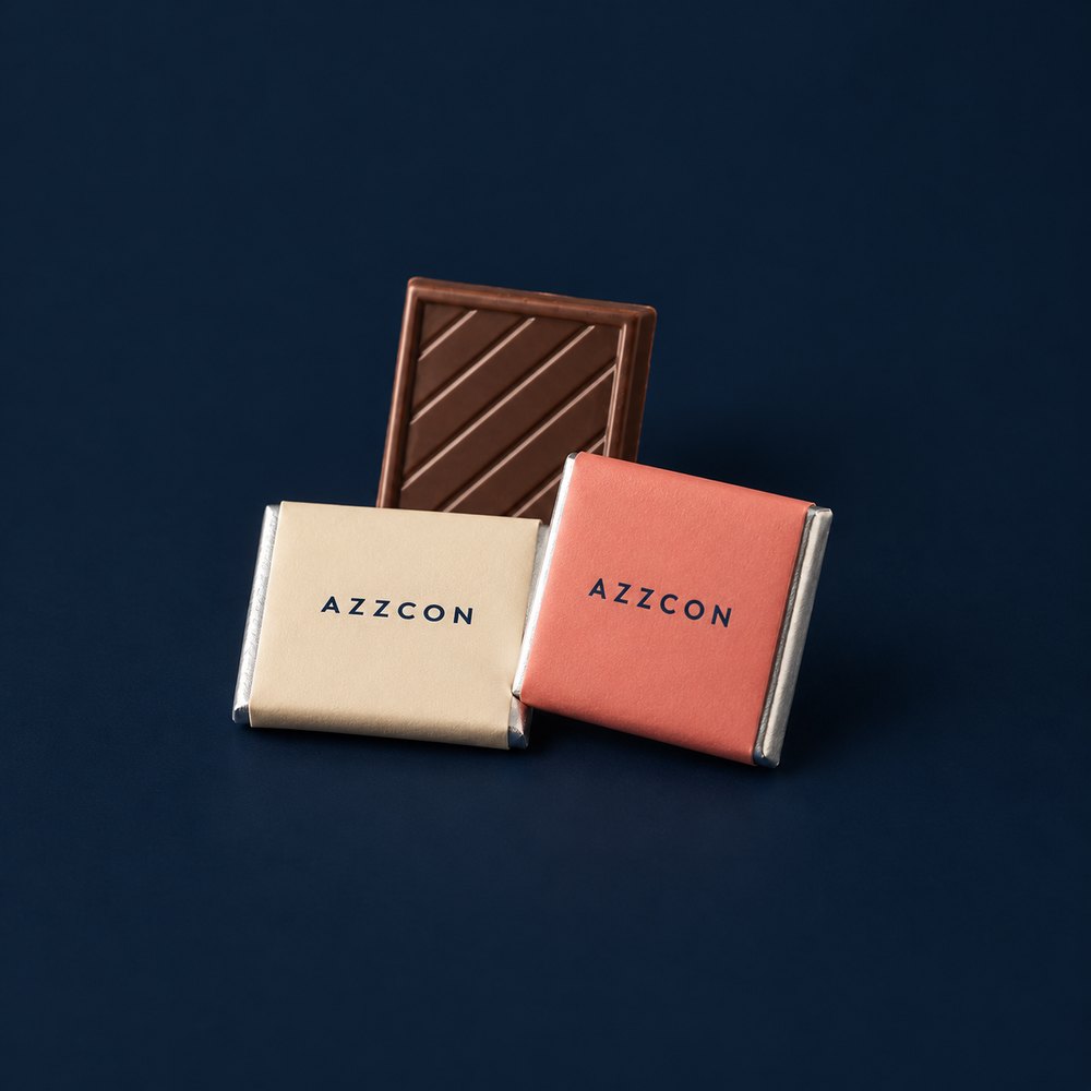 Chokladkvadrater med beige och korallfärgade Azzcon-omslag på marin bakgrund